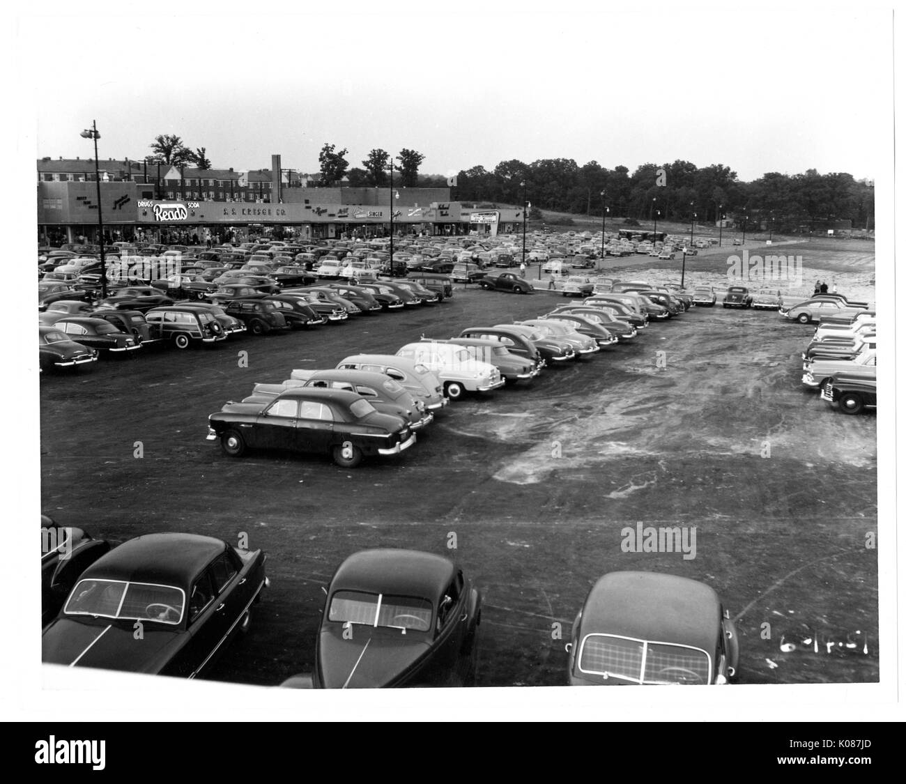 Parcheggio di Northwood Shopping Centre, un sacco di automobili parcheggiate, parcheggio accanto ai negozi come legge, gli alberi e i lampioni anche in background, Baltimore, Maryland, 1950. Foto Stock