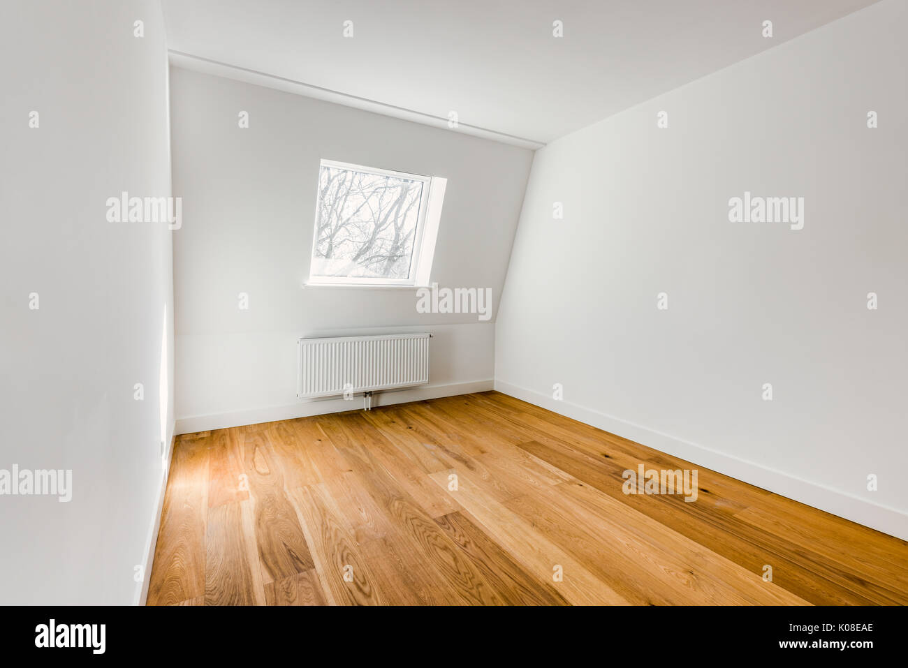 Svuotare la camera interna con pavimento in legno duro, radiatore e finestra Foto Stock