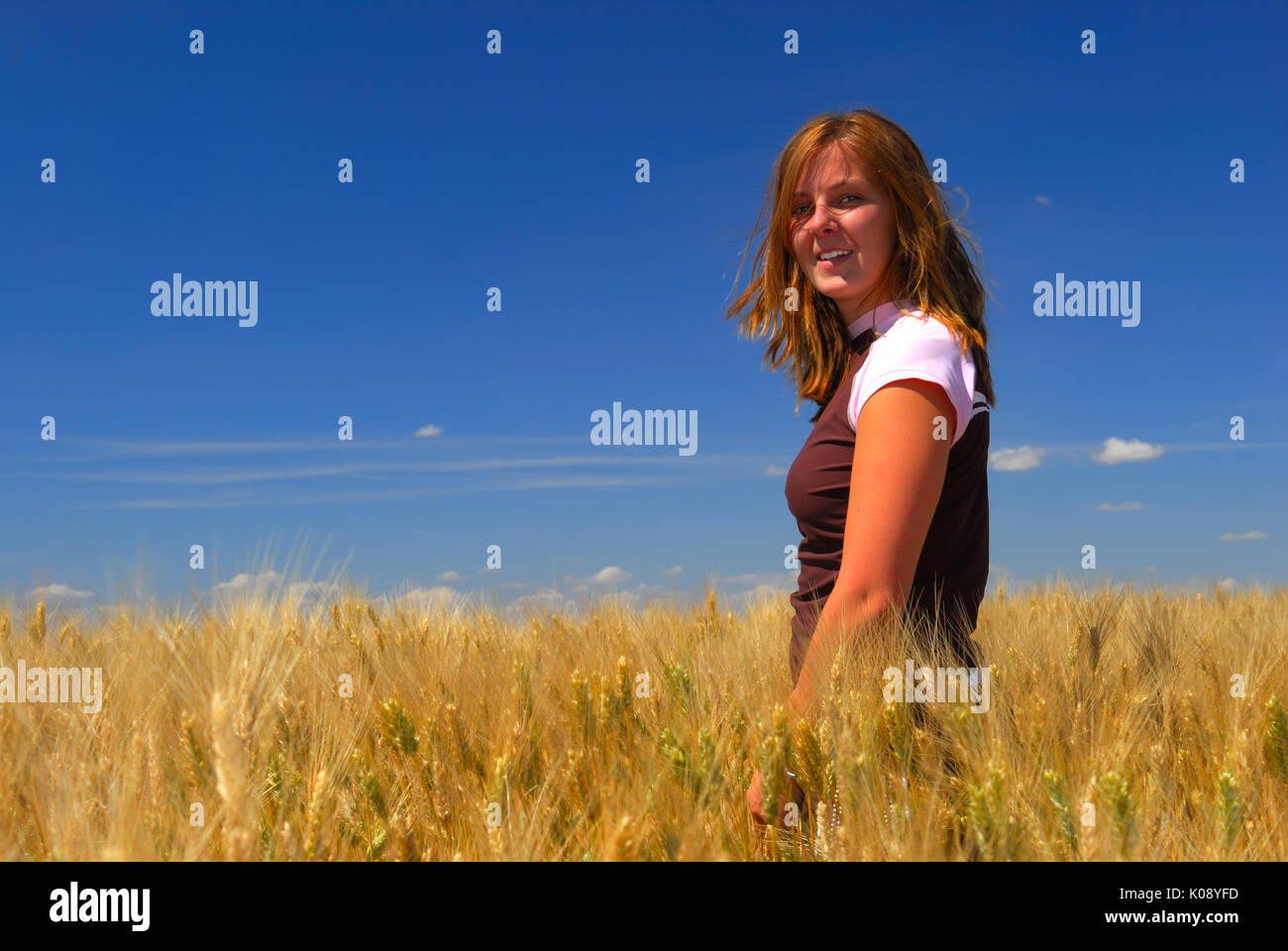 Piuttosto giovane donna si erge nel frumento duro campo sulla splendida giornata estiva. Foto Stock