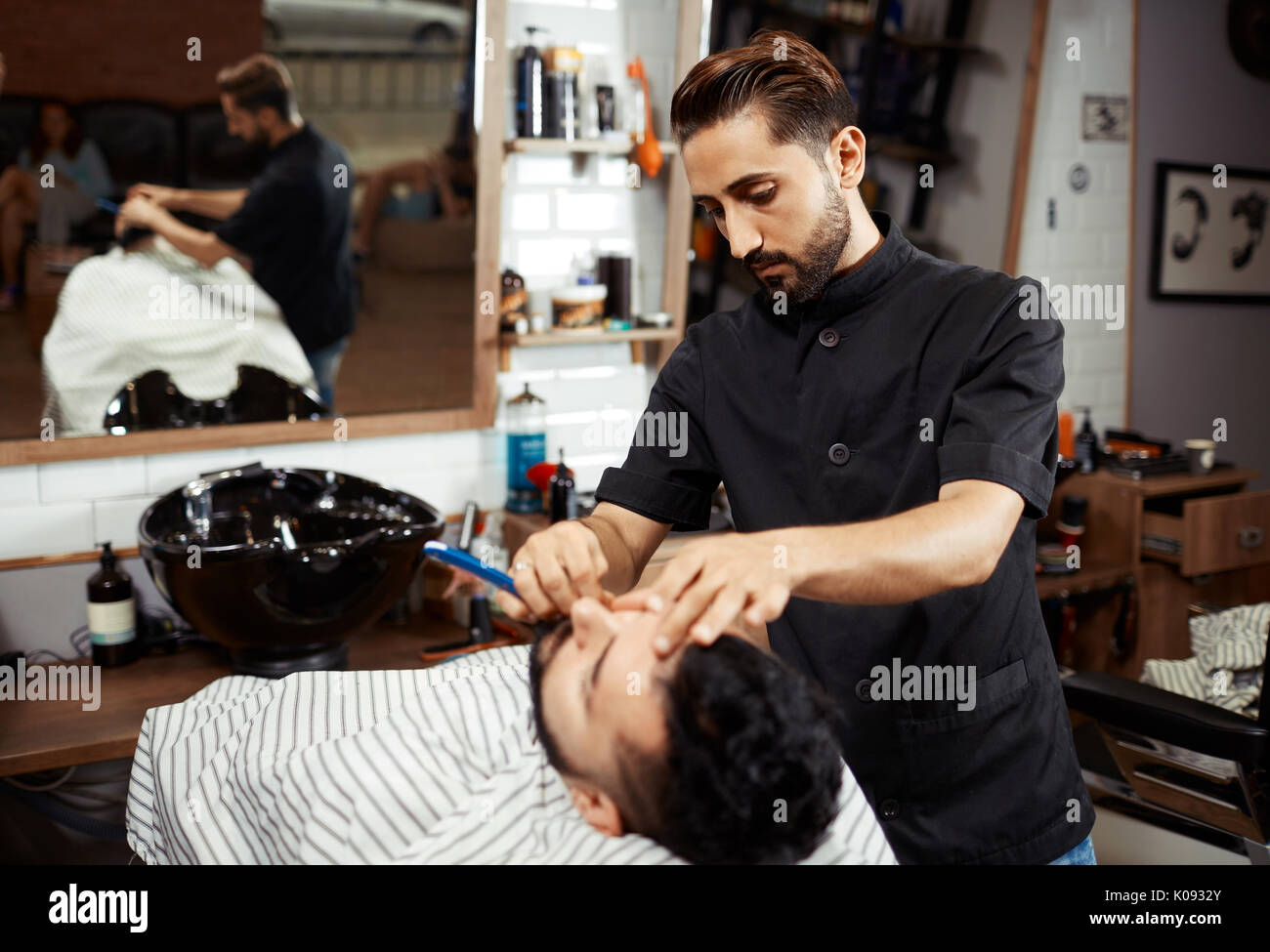 Rasoio a lavorare con il cliente in salone Foto Stock