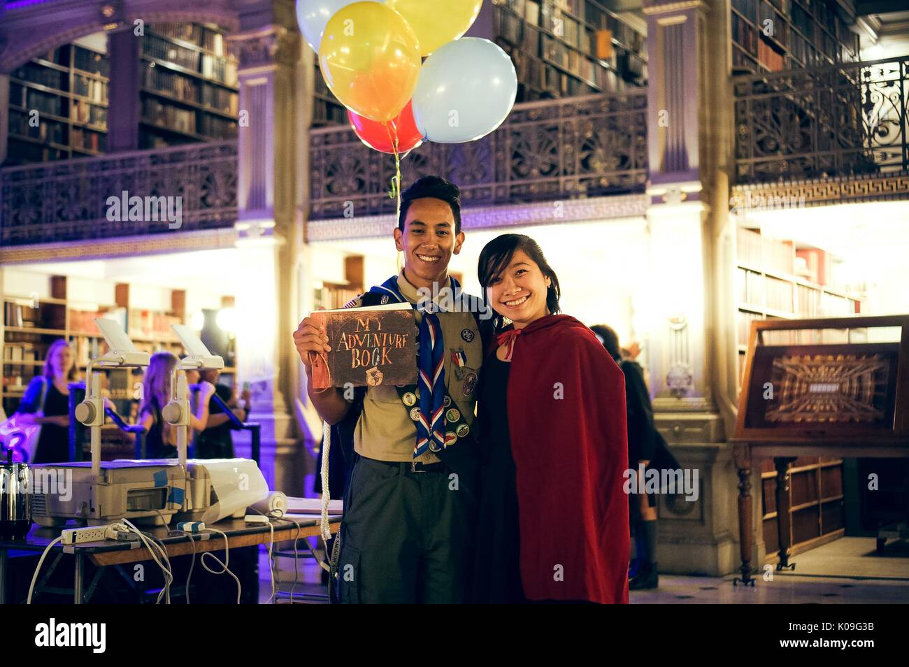 Due studenti del college posano con le loro braccia intorno a ciascun altro, il ragazzo è vestito come il personaggio principale del film 'Up' e la bambina indossa un abito nero e un mantello rosso, 2015. Foto Stock