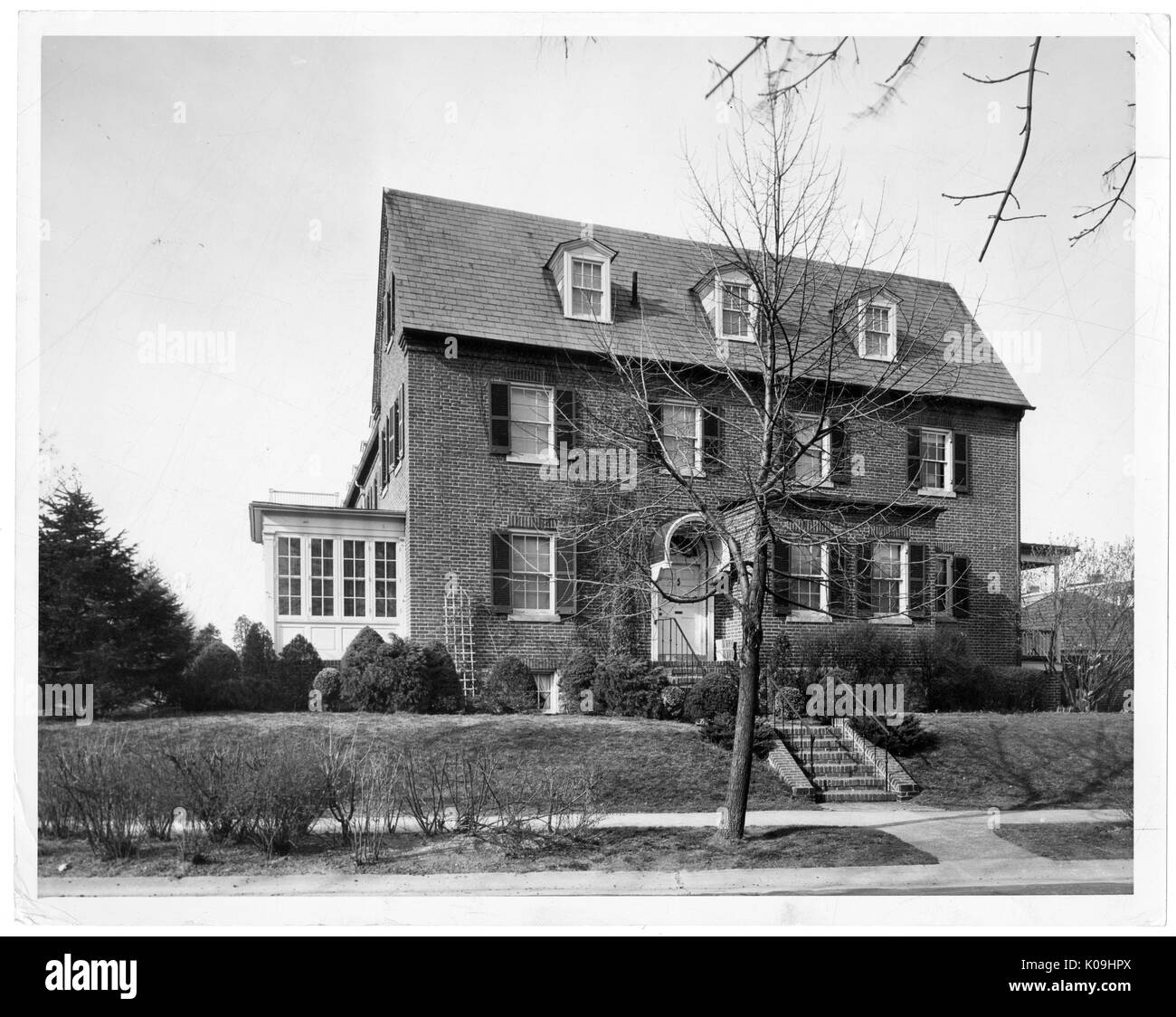 Fotografia di una a tre piani in mattoni casa nel quartiere di Guilford a Baltimore con una facciata simpple, con scale che conducono al portico anteriore, erba Morta e una sterile prato anteriore con morti alberi e cespugli che circondano la casa, Baltimore, Maryland, 1935. Questa immagine viene da una serie di documentare la costruzione e la vendita di case nel parco di Roland/Guilford quartiere di Baltimora, un tram sobborgo e una delle prime comunità prevista negli Stati Uniti. Il quartiere era segregato ed è considerato uno dei primi esempi di applicazione della segregazione razziale attraverso l uso di restric Foto Stock