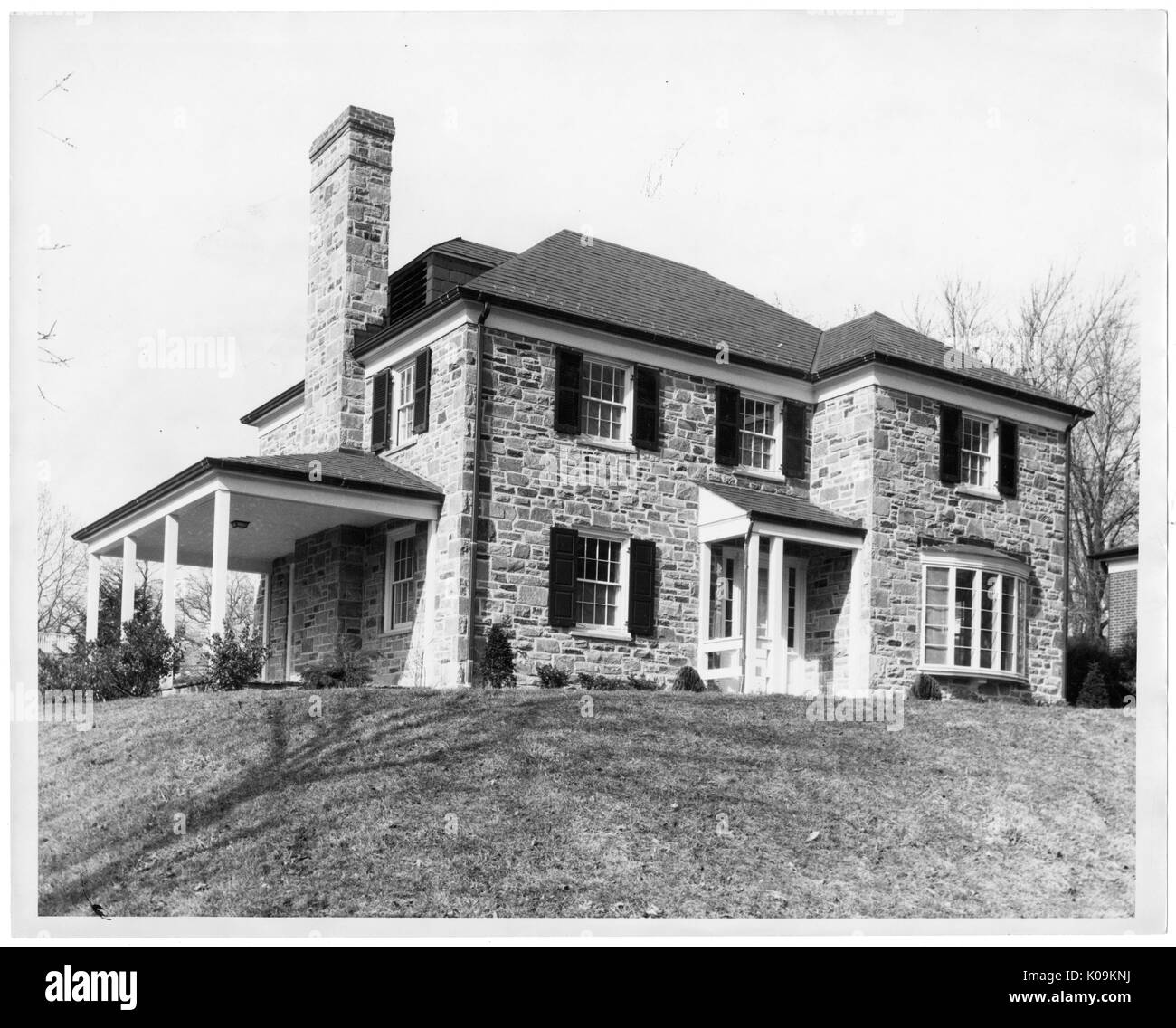 Paesaggio girato di una casa a due piani con un portico permanente di entrata e un lato porticato, un camino in pietra, sulla cima di una piccola collina erbosa, alberi con foglie non dietro la casa, Roland parco/Guilford, Baltimore, Maryland, 1910. Questa immagine viene da una serie di documentare la costruzione e la vendita di case nel parco di Roland/Guilford quartiere di Baltimora, un tram sobborgo e una delle prime comunità prevista negli Stati Uniti. Il quartiere era segregato ed è considerato uno dei primi esempi di applicazione della segregazione razziale attraverso l'uso limitato di patti. Foto Stock