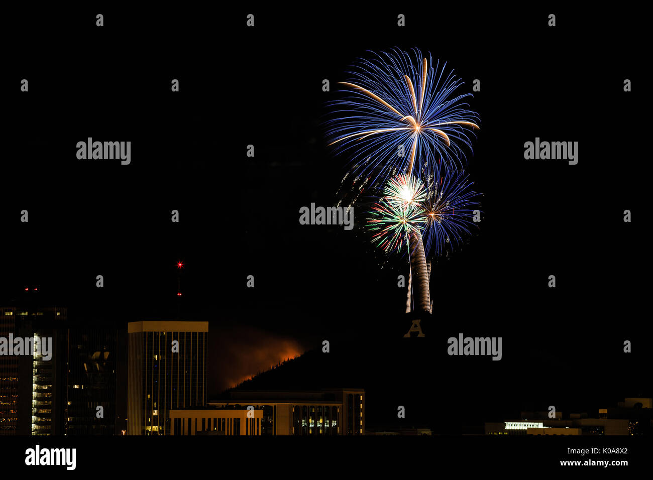 Luce di fuochi d'artificio il cielo di Tucson e accende un fuoco su "A" montagna per il 4 di luglio la celebrazione. Foto Stock