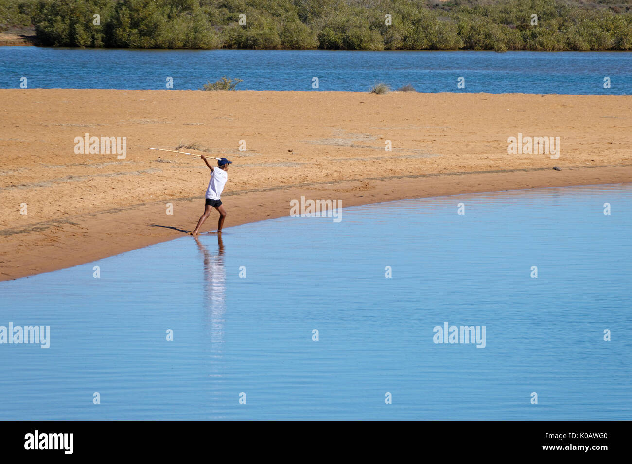 Giovane uomo aborigeno gettando lancia in acqua, il tentativo di catturare i pesci, Carnarvon, Gascoyne, Australia occidentale Foto Stock