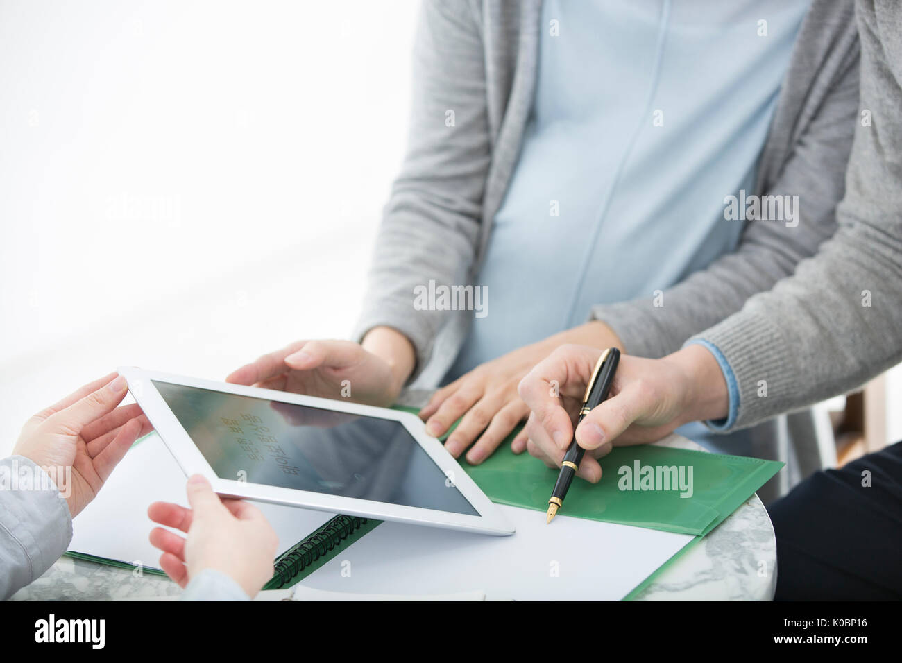 Medico che mostra il tablet PC alla moglie incinta e suo marito Foto Stock