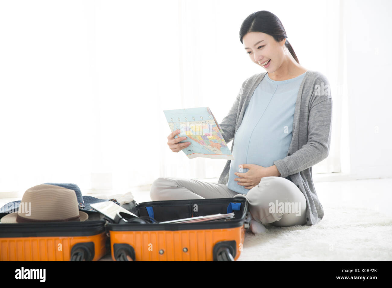 Sorridente donna incinta preparazione del viaggio Foto Stock