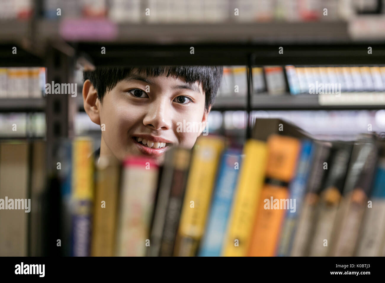 Ritratto di scuola sorridente ragazzo in biblioteca Foto Stock