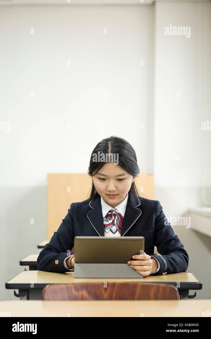 Ritratto di scuola sorridente ragazza con tavoletta elettrico in aula Foto Stock