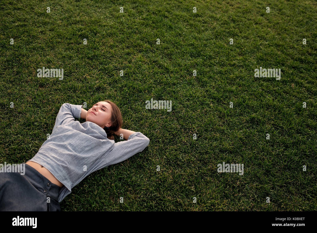 Bellissima giovane donna europea stabilisce su erba e appoggi Foto Stock