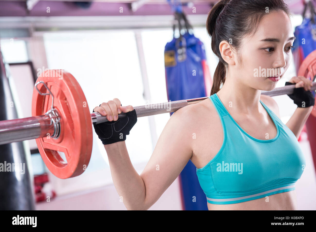 Vista laterale Ritratto di giovane donna in sportswear sollevamento pesi al club della salute Foto Stock