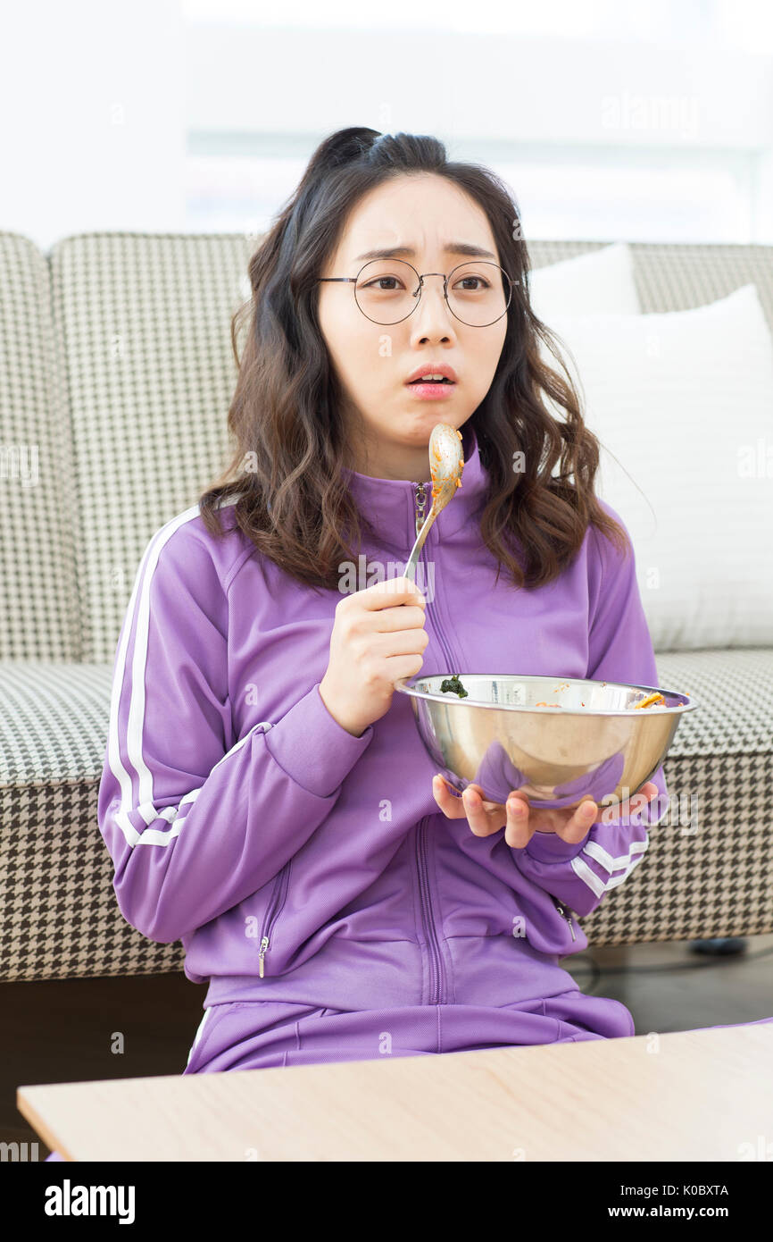 Giovani NEET donna guardando la TV mangiare pasti Foto Stock