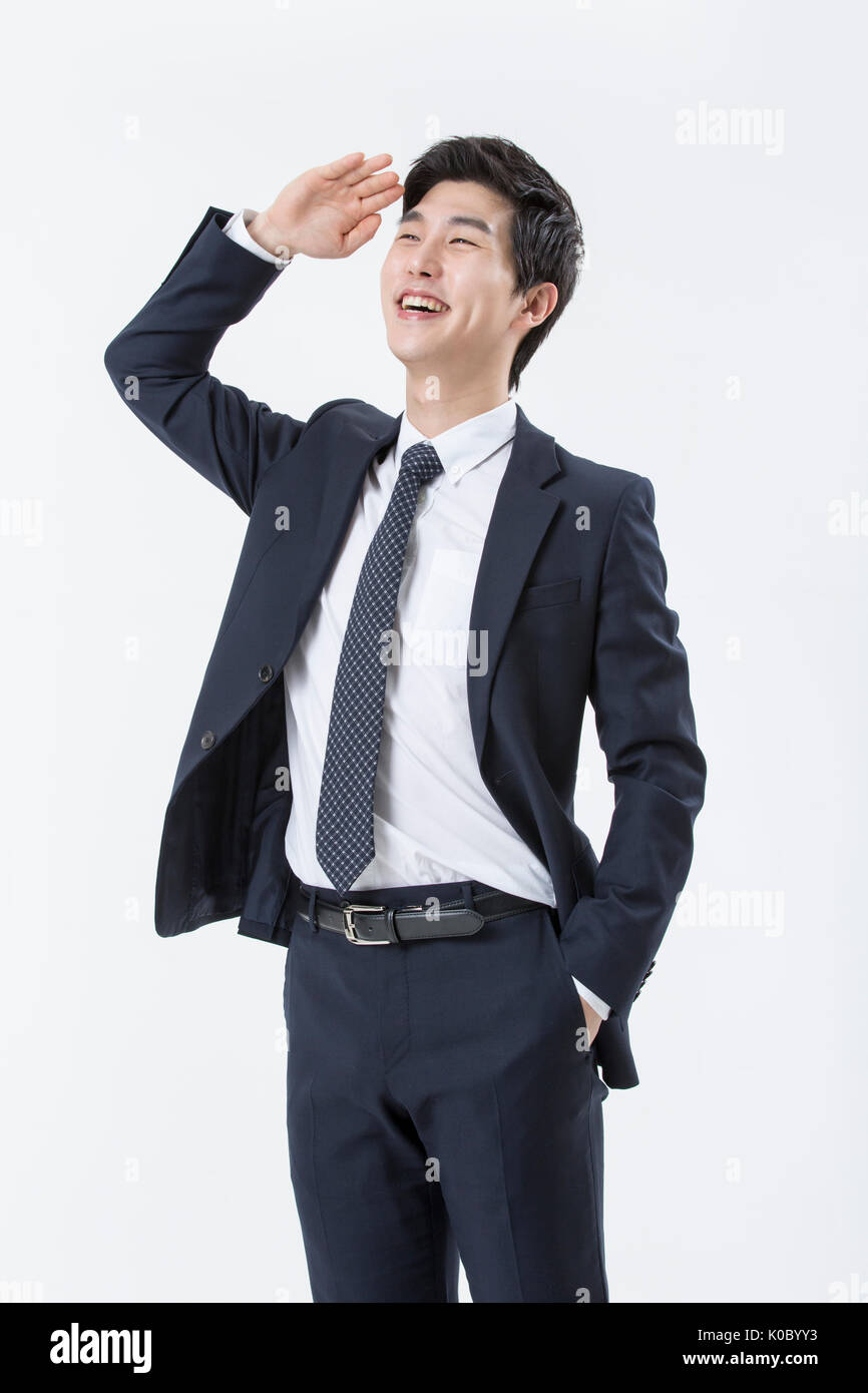 Giovane imprenditore sorridente in tuta in piedi guardando intorno Foto Stock