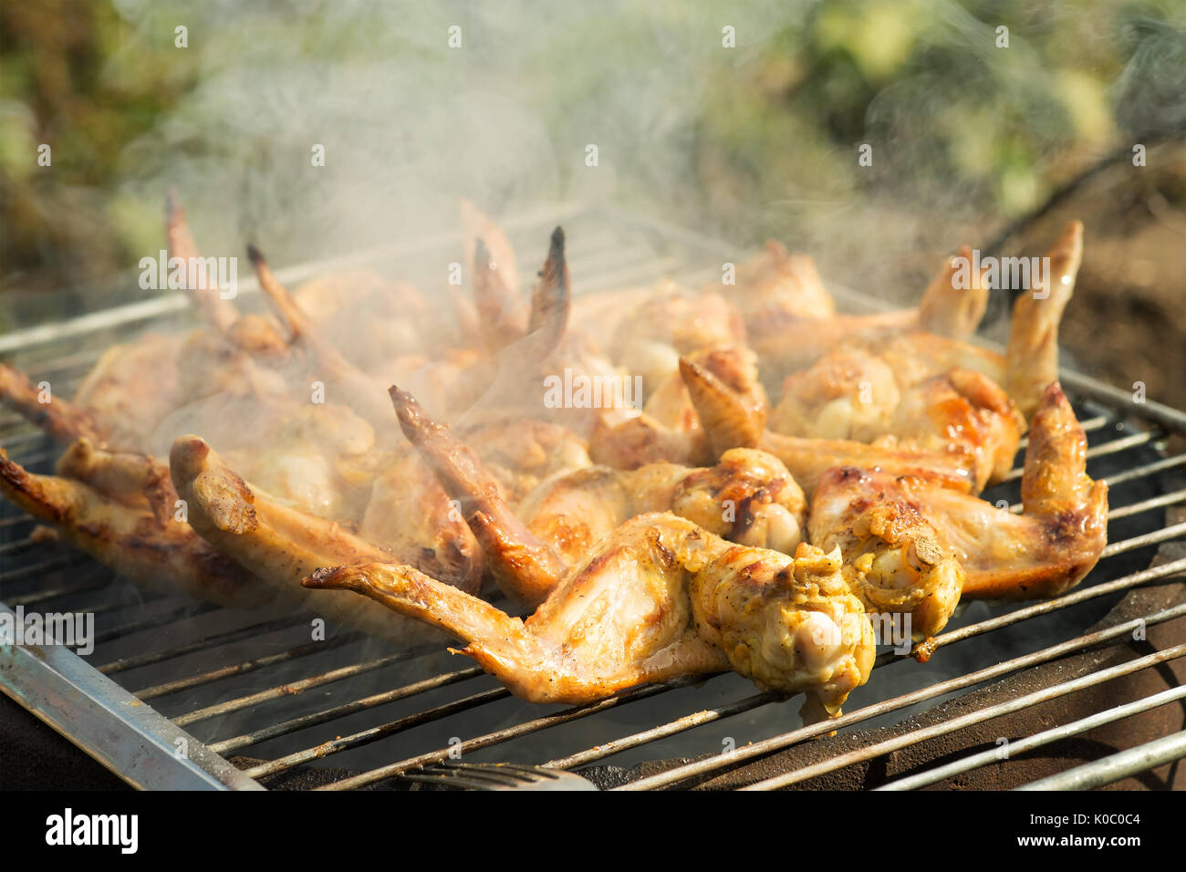 La cottura di ali di pollo a fuoco Foto Stock