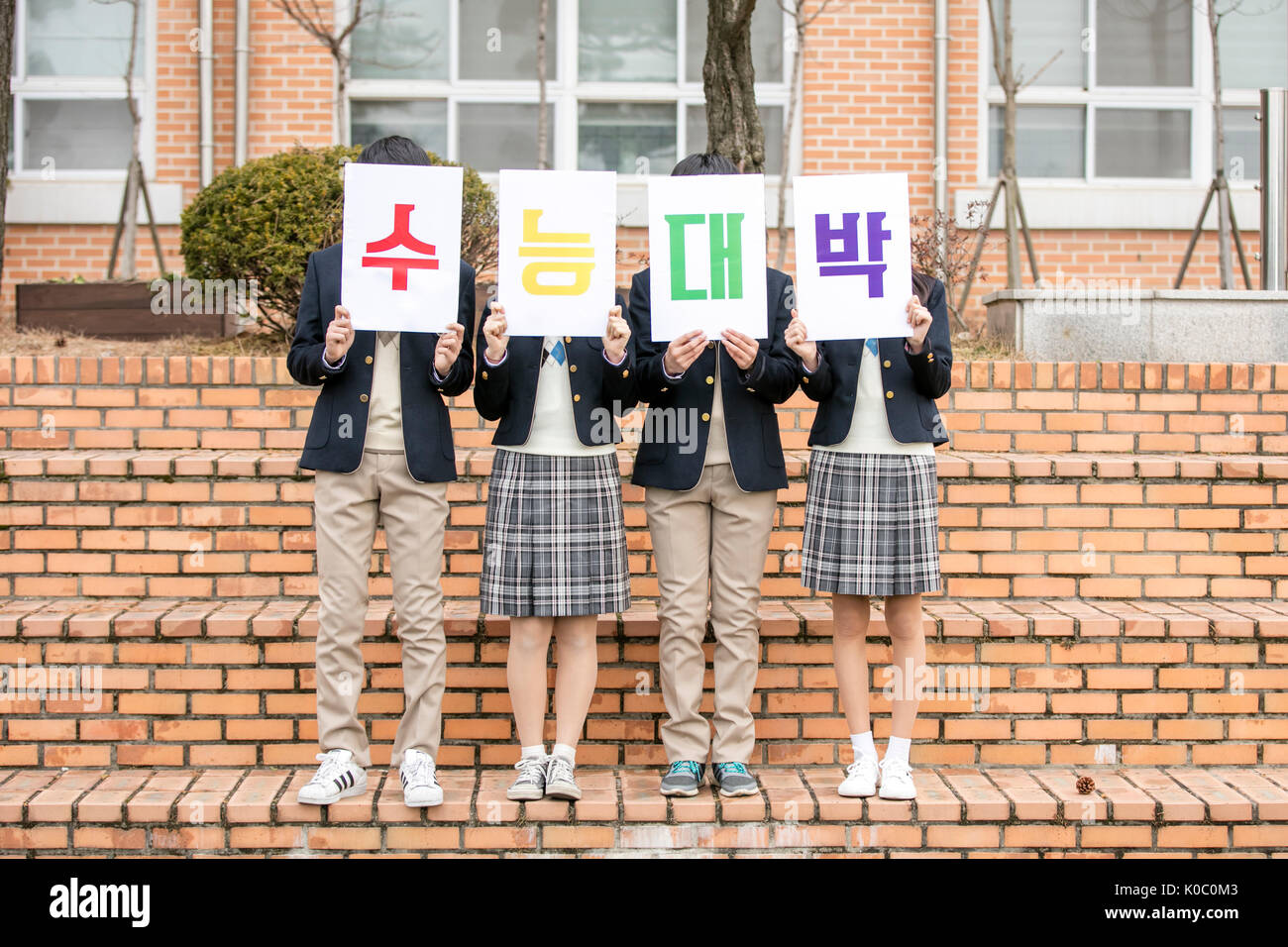 Quattro gli studenti della scuola con il tifo messaggio per examinees in piedi a fianco a fianco Foto Stock