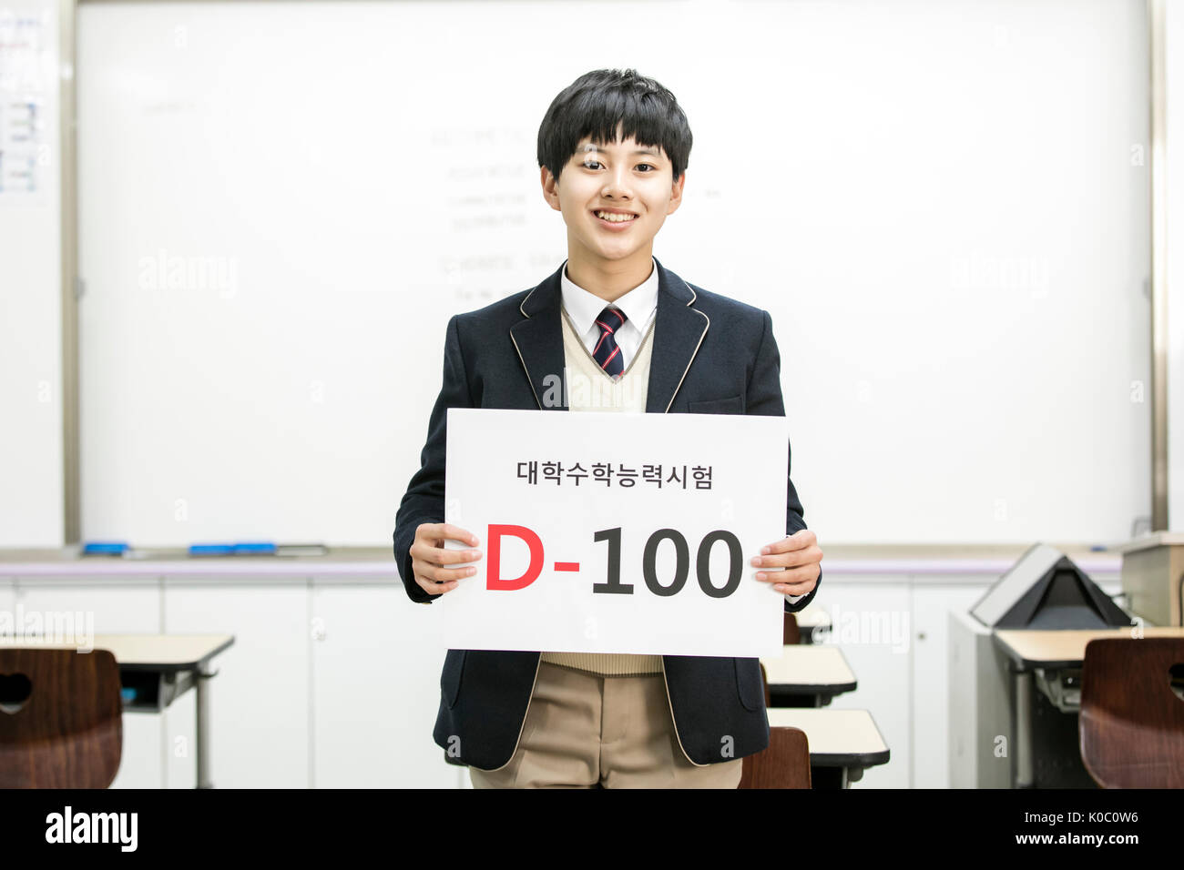 Sorridente scuola coreana ragazzo che mostra una targhetta Foto Stock