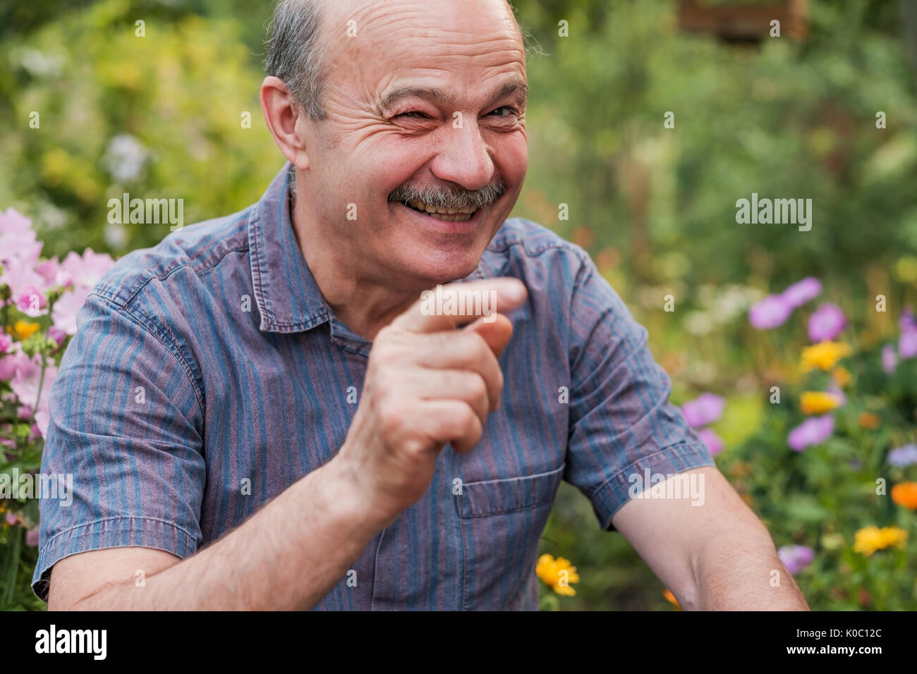Sorridente attraente uomo senior di guardare direttamente la fotocamera e ridere Foto Stock