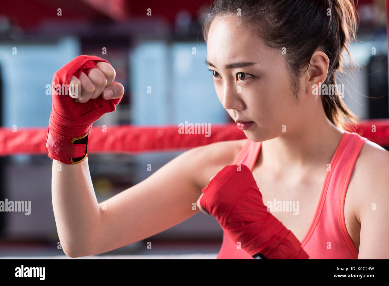 Vista laterale verticale del boxer femmina in posa stringendo la sua a suon di pugni Foto Stock