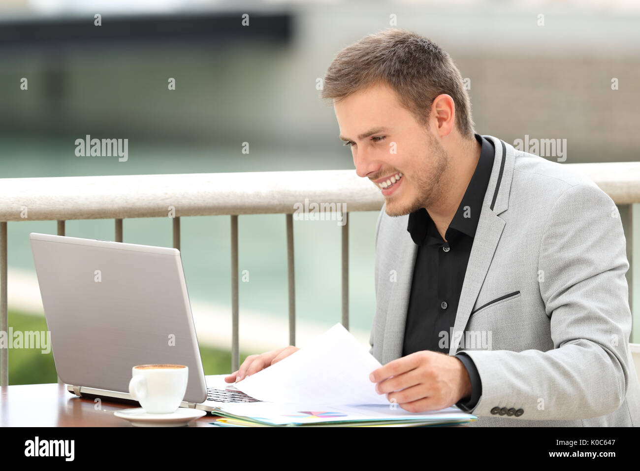 Singola executive felice consultazione on line il contenuto in un computer portatile seduti in un caffè Foto Stock