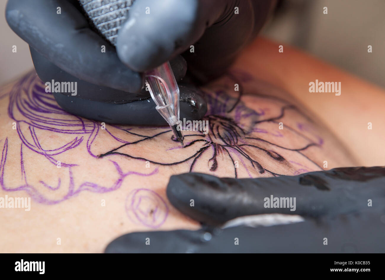 Femmina artista del tatuaggio tattoo si applica alla spalla di una donna. È lei che delinea il tatuaggio Foto Stock
