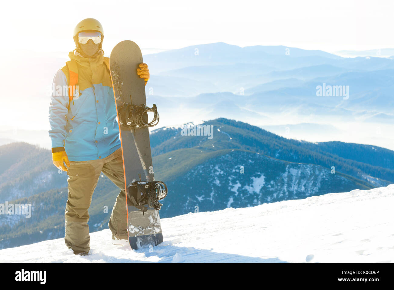 Snowboarder in piedi accanto a snowboard spinto nella neve con uno splendido scenario con sun-set sullo sfondo Foto Stock