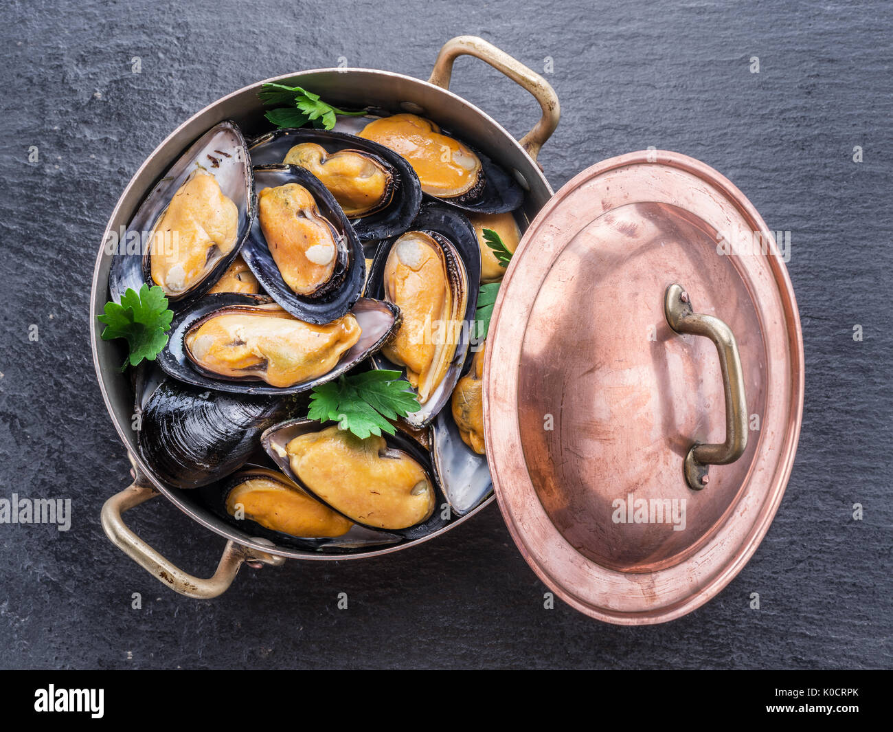 Bollito di cozze in padella di rame su sfondo di grafite. Foto Stock