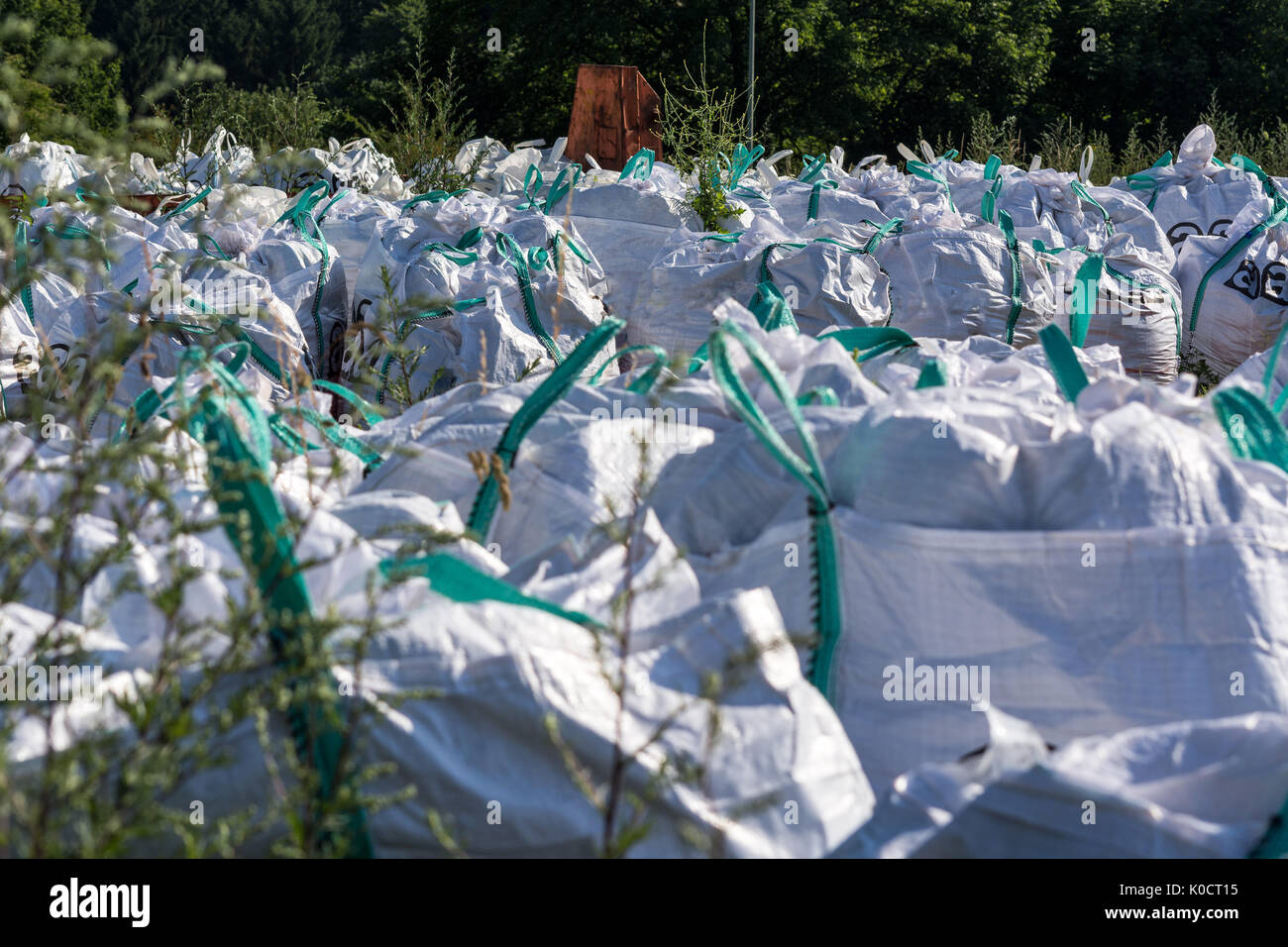 Amianto con segnale di avvertimento di scritte in tedesco "a" per amianto amianto memorizzati in grossi sacchi e sacchetti di carta o tessuto borsa su lo spazio aperto di un constructi Foto Stock