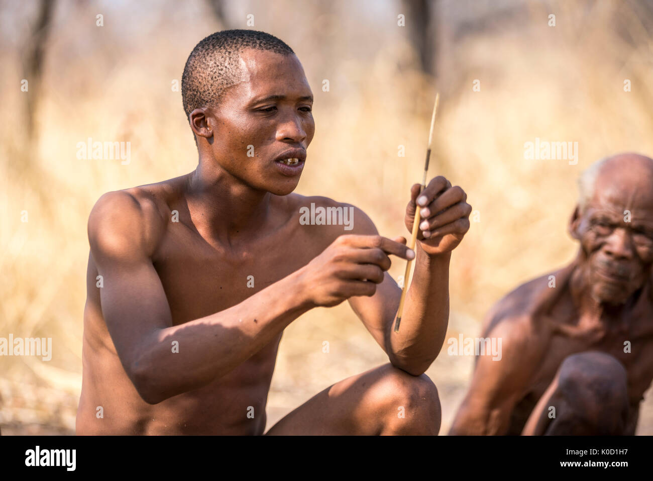 Saan giovane uomo che lavora in cacciatori boscimani Storia viva Village. Grashoek, Otjozondjupa, Namibia, Africa. Foto Stock