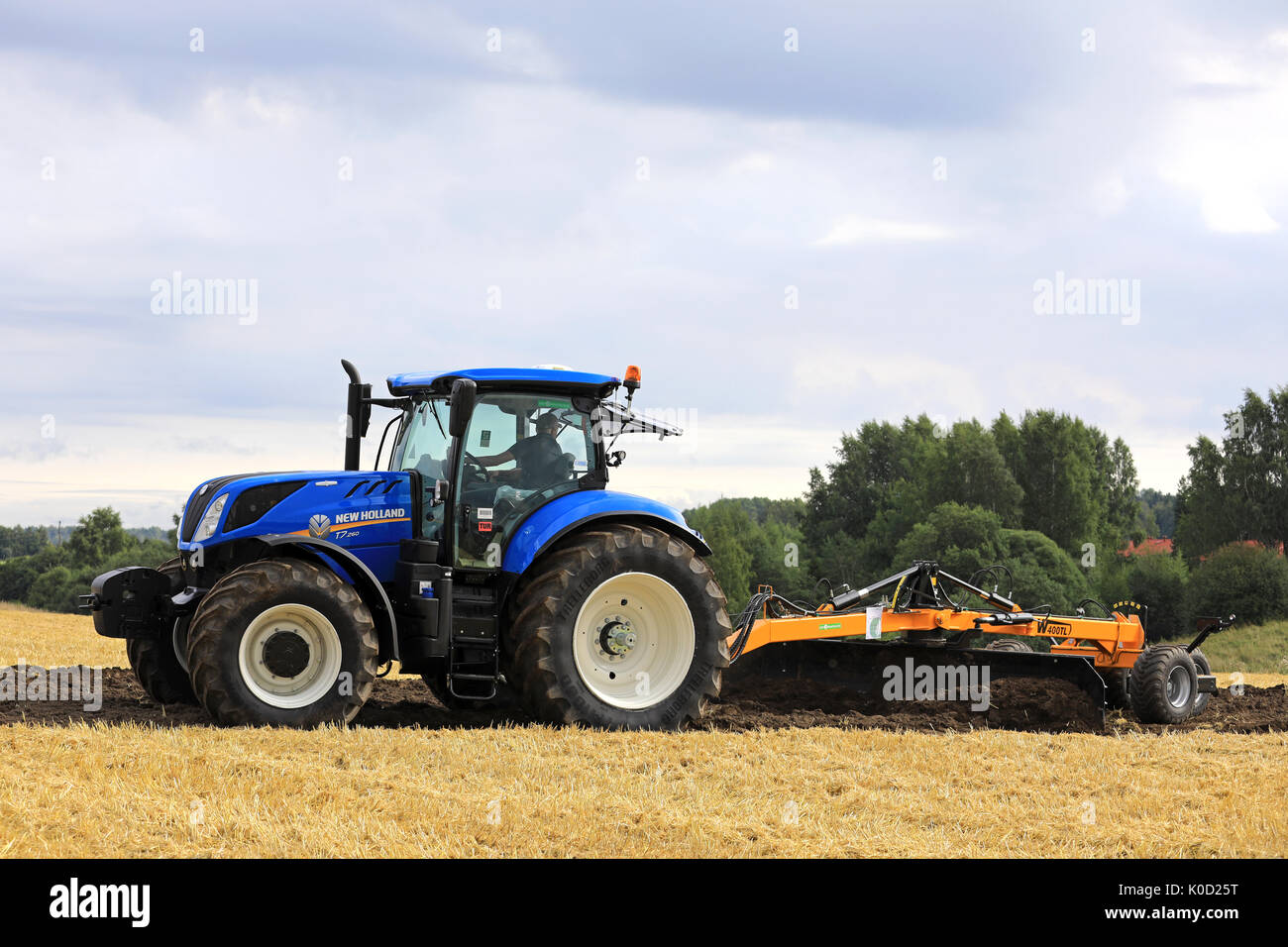 SALO, Finlandia - 18 agosto 2017: agricoltore lavora con New Holland T7.260 trattore e W400-TL livellatore di campo su Puontin Peltopaivat Harvestin agricoli Foto Stock