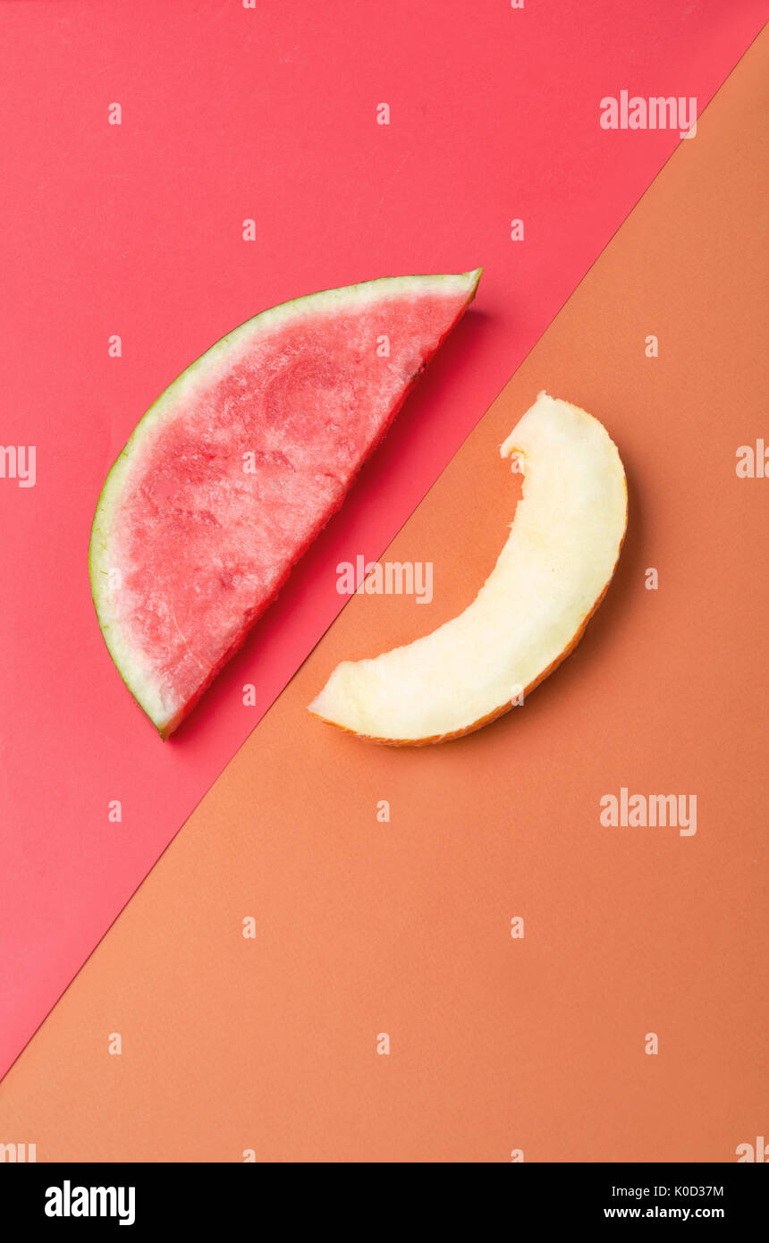 Fetta di anguria con pietre su sfondo rosso e melone isolate su sfondo arancione Foto Stock