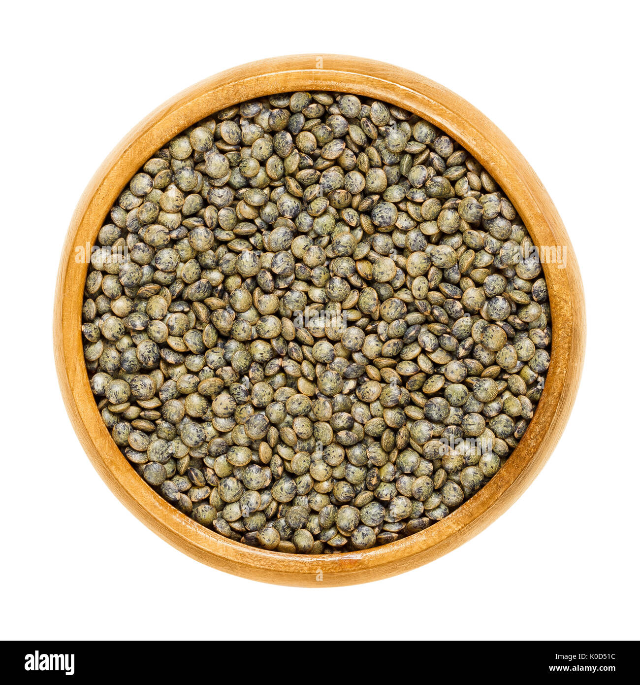 Le Puy lenticchie verdi nella ciotola di legno. Essiccato piccolo grigio ardesia semi di Lens esculenta puyensis da Le Puy in Auvergne, Francia. Foto Stock