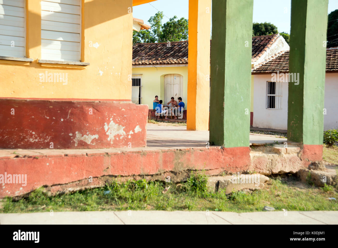 Inquadrata tramite una casa coloniale pilastri di un gruppo di uomini cubani la riproduzione dei dominos nel portico di una casa nelle stradine di Trinidad, Cuba Foto Stock