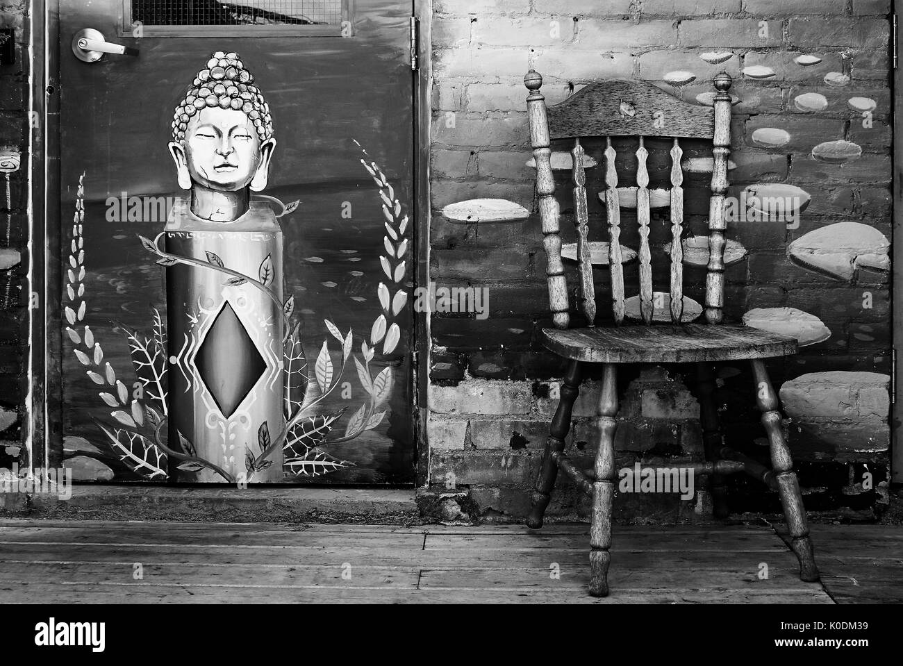 Murale di buddha accanto alla sedia contro la parete (bianco e nero) Foto Stock