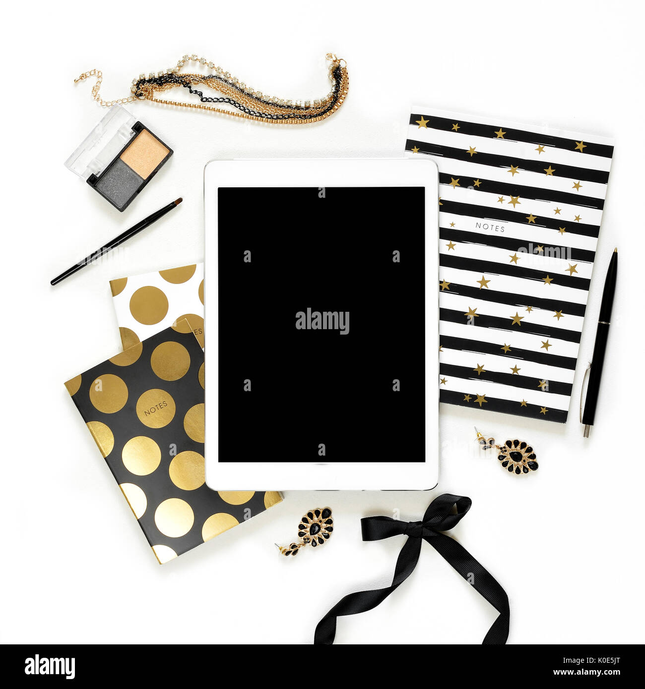 Appartamento laico femminile di moda home office area di lavoro con la tavoletta, nero elegante notebook d'oro, di cosmetici e di gioielli su sfondo bianco. vista dall'alto sulla donna lavoro di business desk Foto Stock