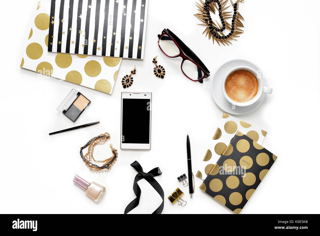 Appartamento laico femminile di moda home office area di lavoro con telefono, tazza di caffè nero elegante notebook d'oro, di cosmetici e di gioielli su sfondo bianco. vista dall'alto sulla donna lavoro di business desk Foto Stock