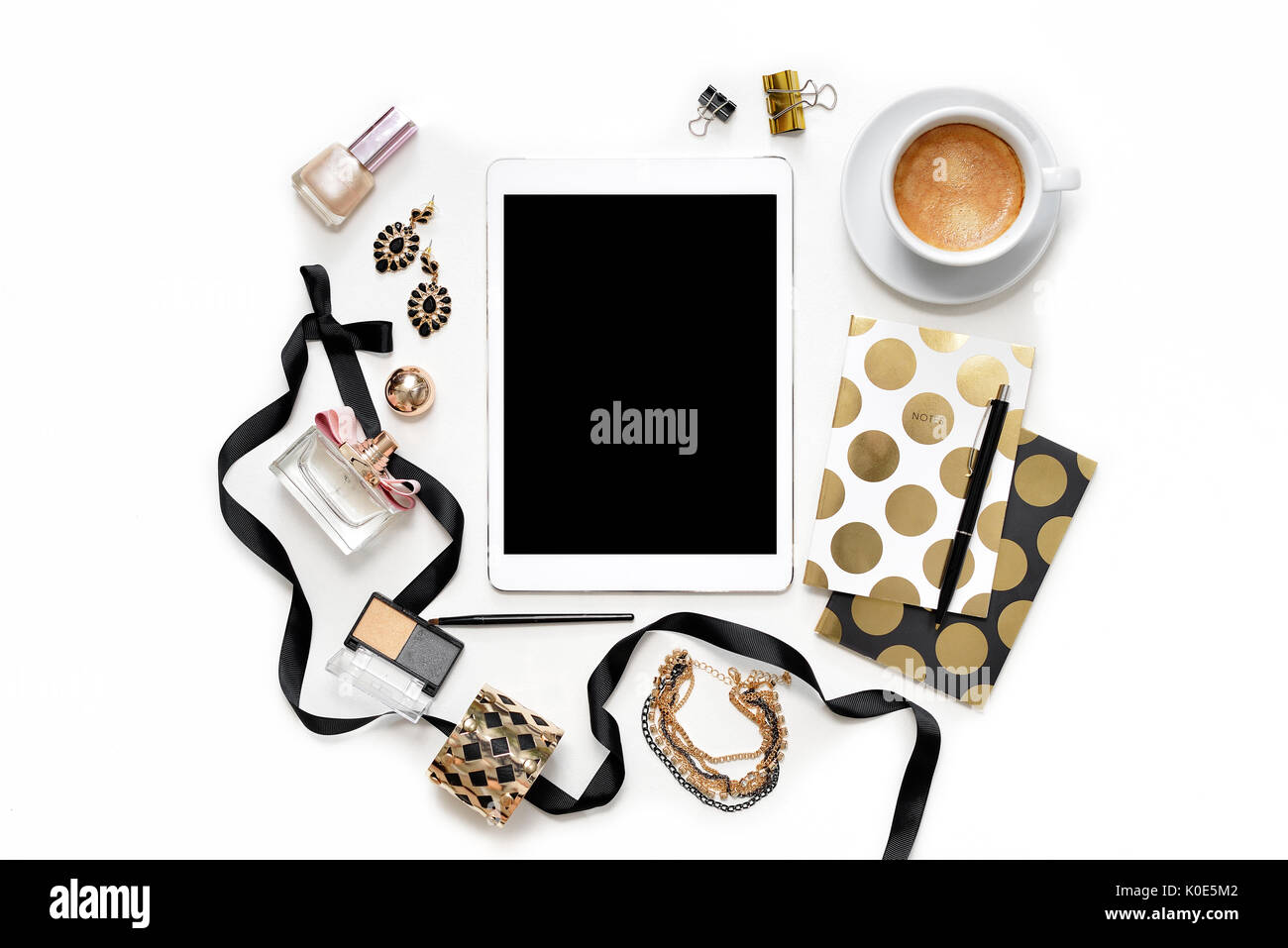 Appartamento laico femminile di moda home office workspace con la compressa, una tazza di caffè nero elegante notebook d'oro, di cosmetici e di gioielli su sfondo bianco. vista dall'alto sulla donna lavoro di business desk Foto Stock