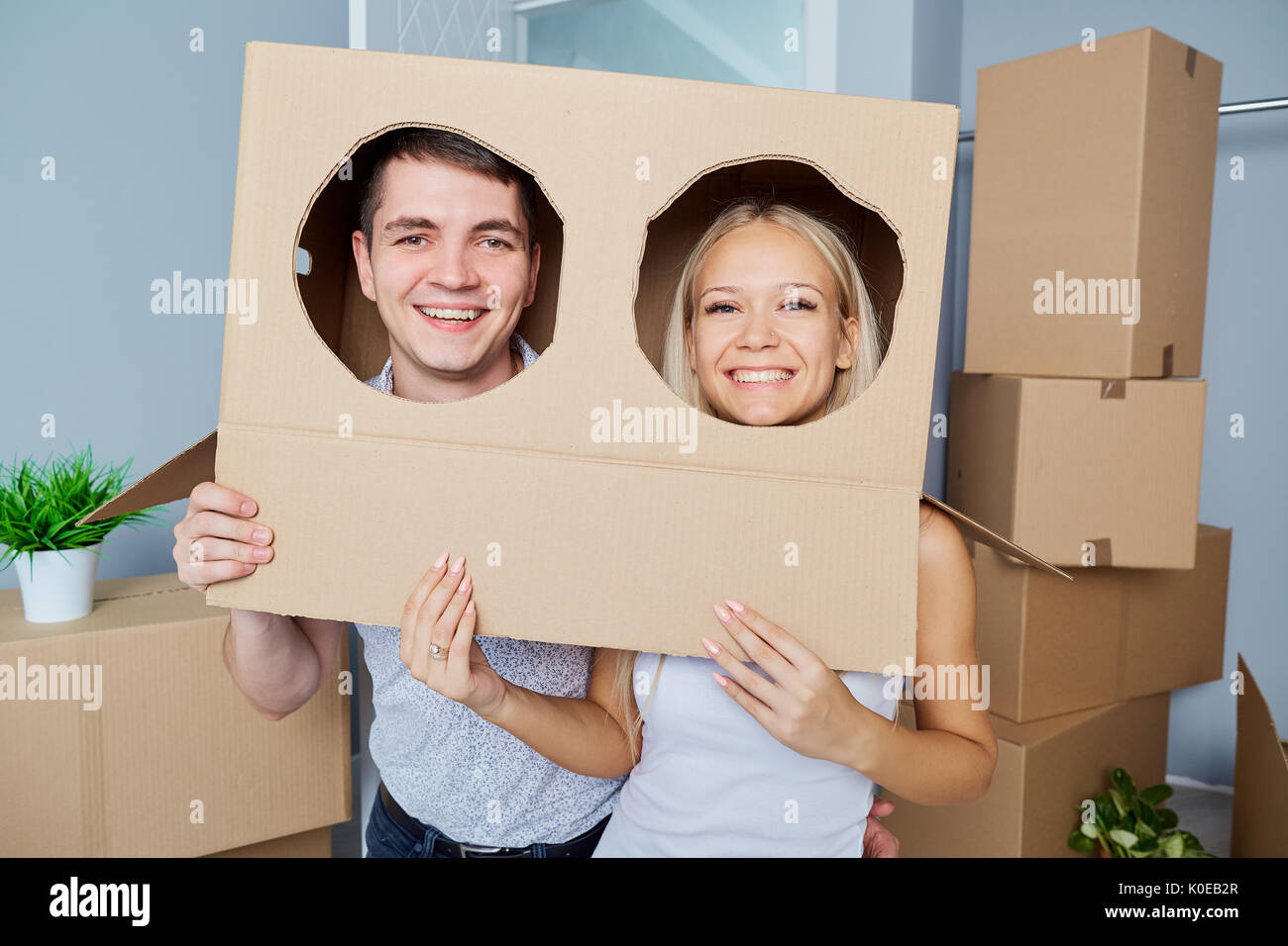 Funny giovane con una scatola sulla testa in una nuova casa. Foto Stock