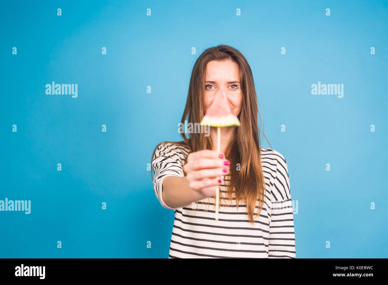 Estate, vacanze, dieta e vegani concetto - Bella sorridente giovane donna holding anguria fetta su stick Foto Stock