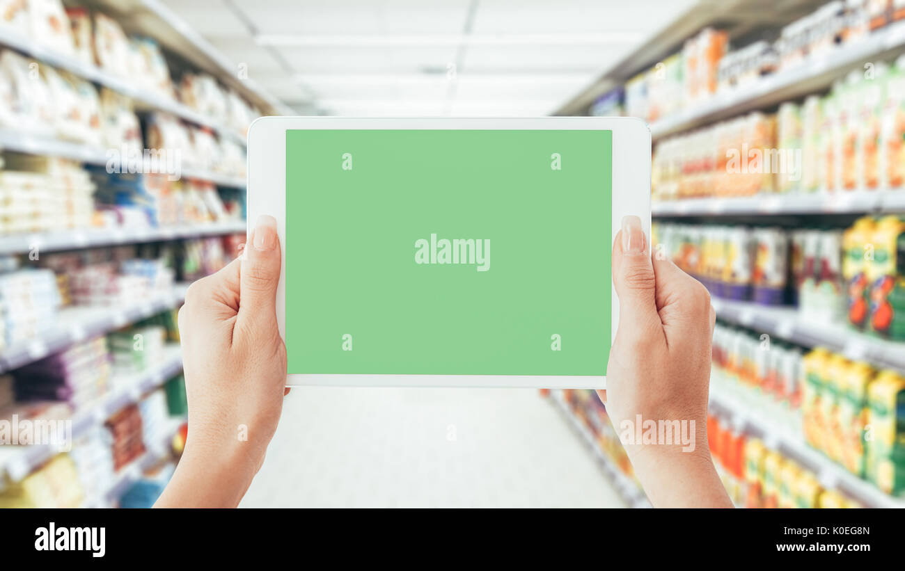 Donna che utilizza una tavoletta digitale nel supermercato corsia: shopping, la tecnologia e la realtà aumentata concept Foto Stock