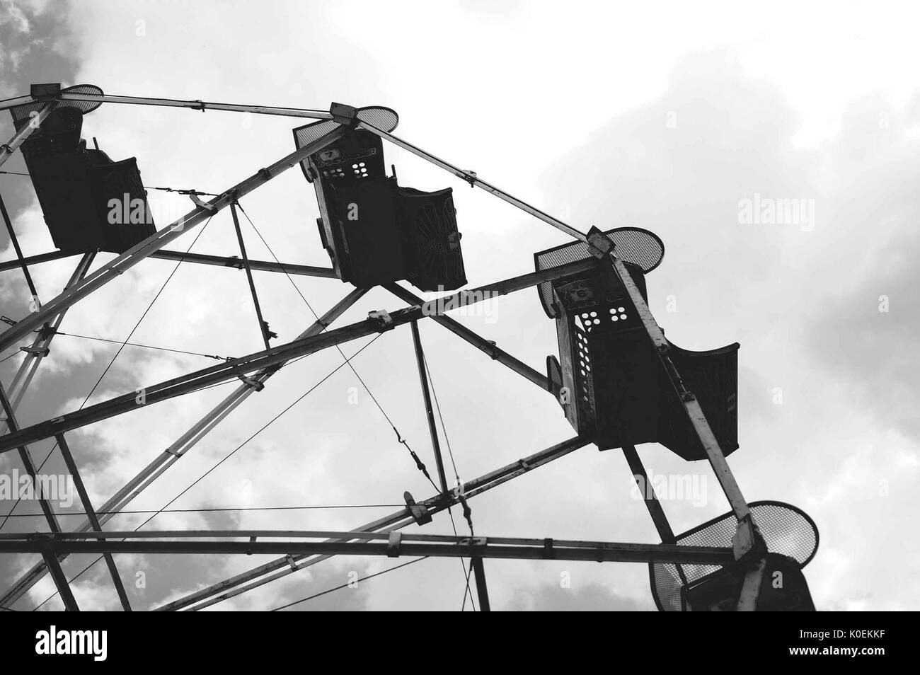 Una bassa angolazione di sedi di ancora un vuoto e la ruota panoramica Ferris ride contro un sfondo nuvoloso durante la fiera di primavera, uno studente-eseguire il carnevale di primavera, alla Johns Hopkins University, Baltimora, Maryland. aprile, 2015. cortesia eric chen. Foto Stock