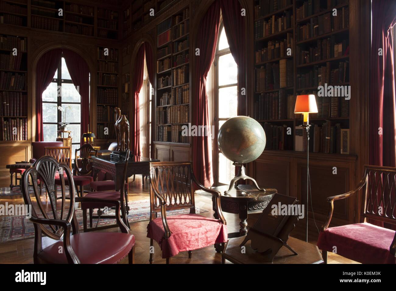 Decorate una stanza di seduta, ci sono un sacco di sedie in legno e built-in linea di scaffali di libri le pareti lungo con finestre da pavimento a soffitto, 2014. cortesia eric chen. Foto Stock