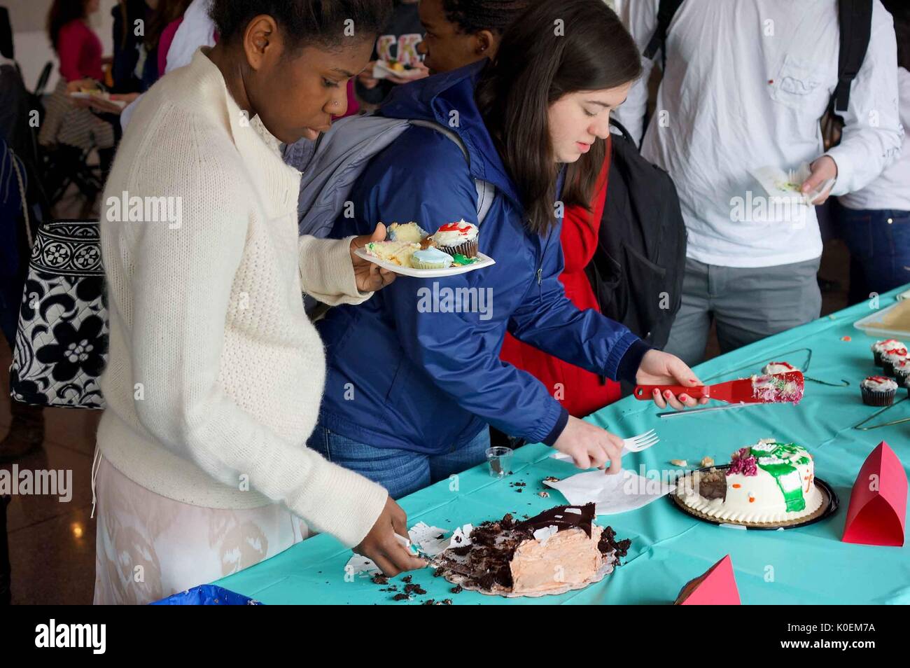 Gli studenti universitari tagliano e mangiano torta al 2014 Edibile Book Festival, una gara di torte letterarie nel campus Homewood della Johns Hopkins University di Baltimora, Maryland, 2014. Cortesia Eric Chen. Foto Stock