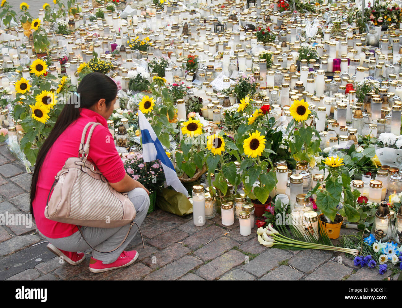 Turku, Finlandia. 22 Ago, 2017. Una donna che è di non-etnica origine finlandese pagando il rispetto per le vittime alla scena di Turku attacco di coltello in cui uno dei due omicidi ha avuto luogo il 18 agosto 2017. Quattro giorni dopo terrosristic rampage persone sono ancora portando fiori e candele memoriale per le vittime a Turku Piazza del Mercato Centrale. Credito: Jukka Palm/Alamy Live news. Foto Stock