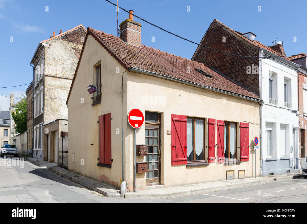 Piccolo angolo casa con colore rosso brillante di persiane alle finestre nella cittadina francese di Saint-Omer in Pas-de-Calais, a nord est della Francia Foto Stock