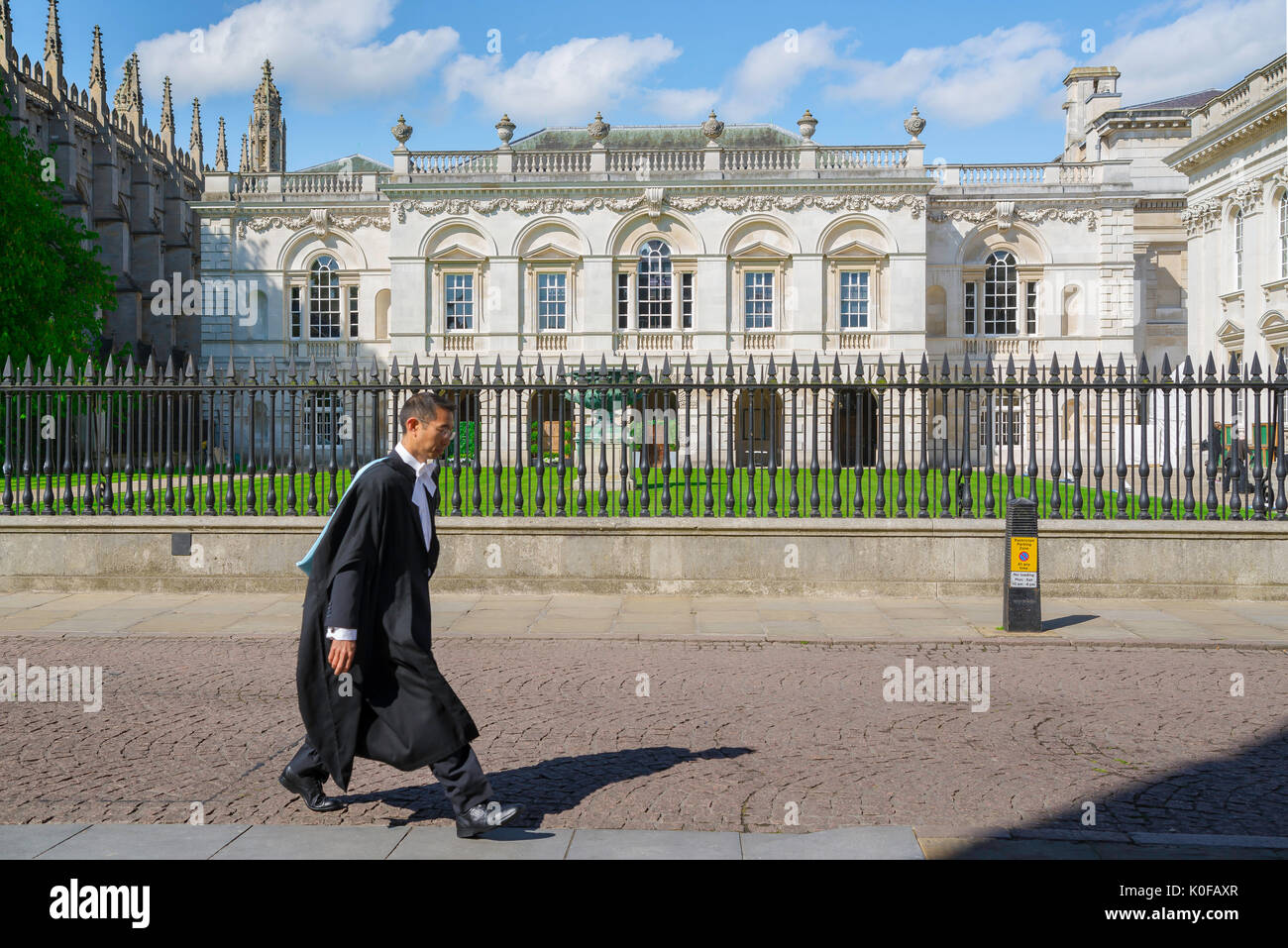 Studente Cambridge Regno Unito, un undergraduate indossa il suo abito di college passeggiate passato l'Università Scuole vecchio edificio in King's Parade, Cambridge, Inghilterra. Foto Stock