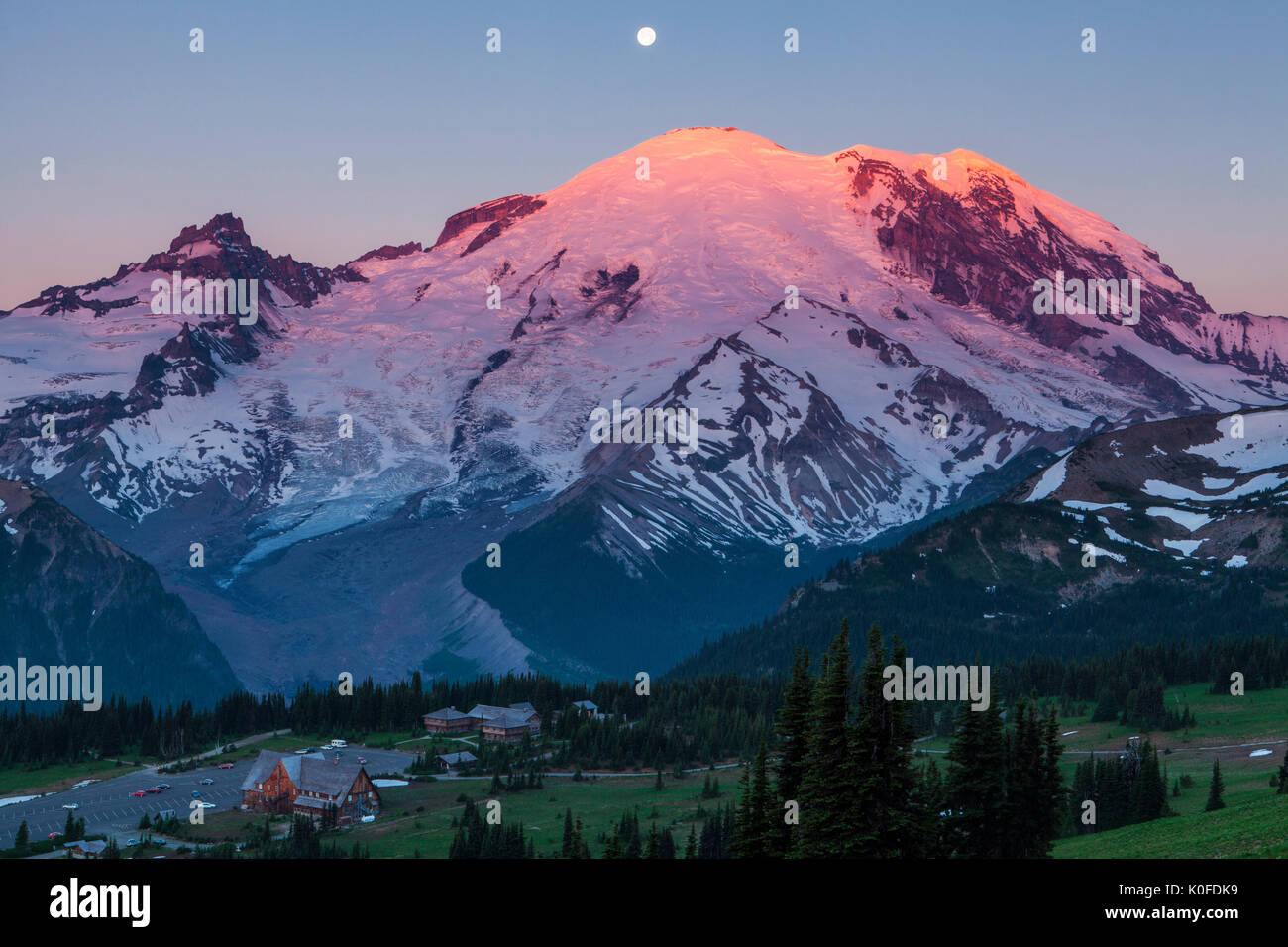 La luna piena splende su Mt. Ranieri e il sorgere del sole all'alba, e il Parco Nazionale del Monte Rainier, Washington, Stati Uniti d'America. Foto Stock