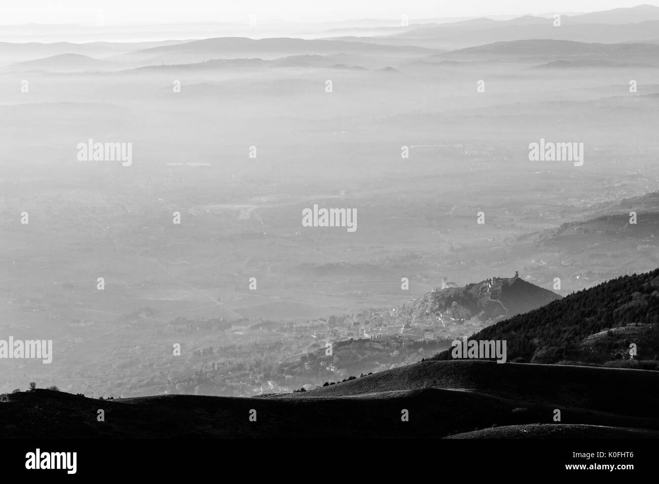 Una veduta aerea della città di Assisi e san.francesco chiesa sopra un mare di nebbia, con lontane colline in background Foto Stock