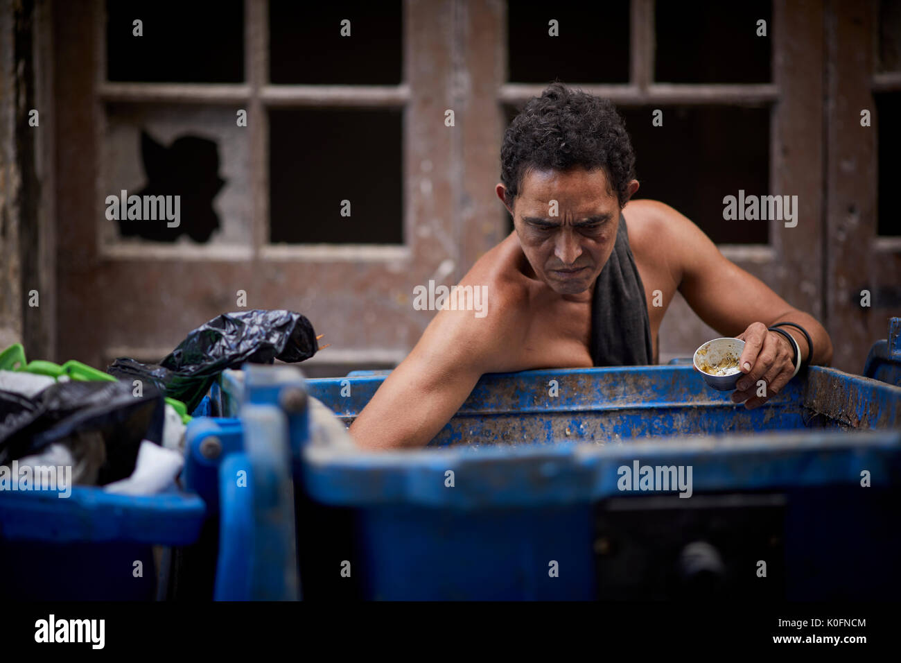 Cubano, Cuba, capitale, Havana un uomo cerca attraverso la spazzatura in un grande contenitore in strada Foto Stock
