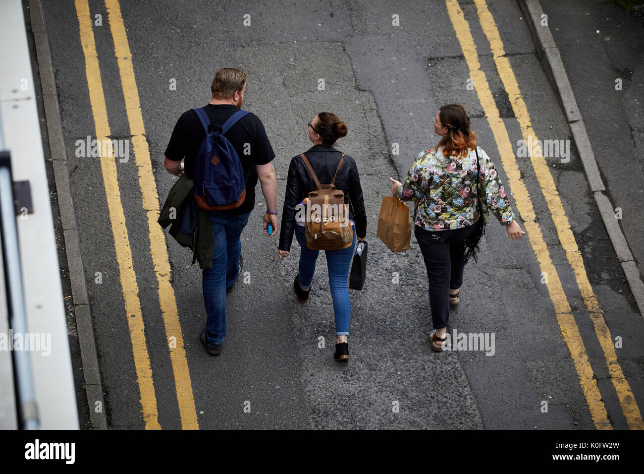 Manchester Northern Quarter pedoni camminando giù per una strada stretta con doppie linee di colore giallo Foto Stock