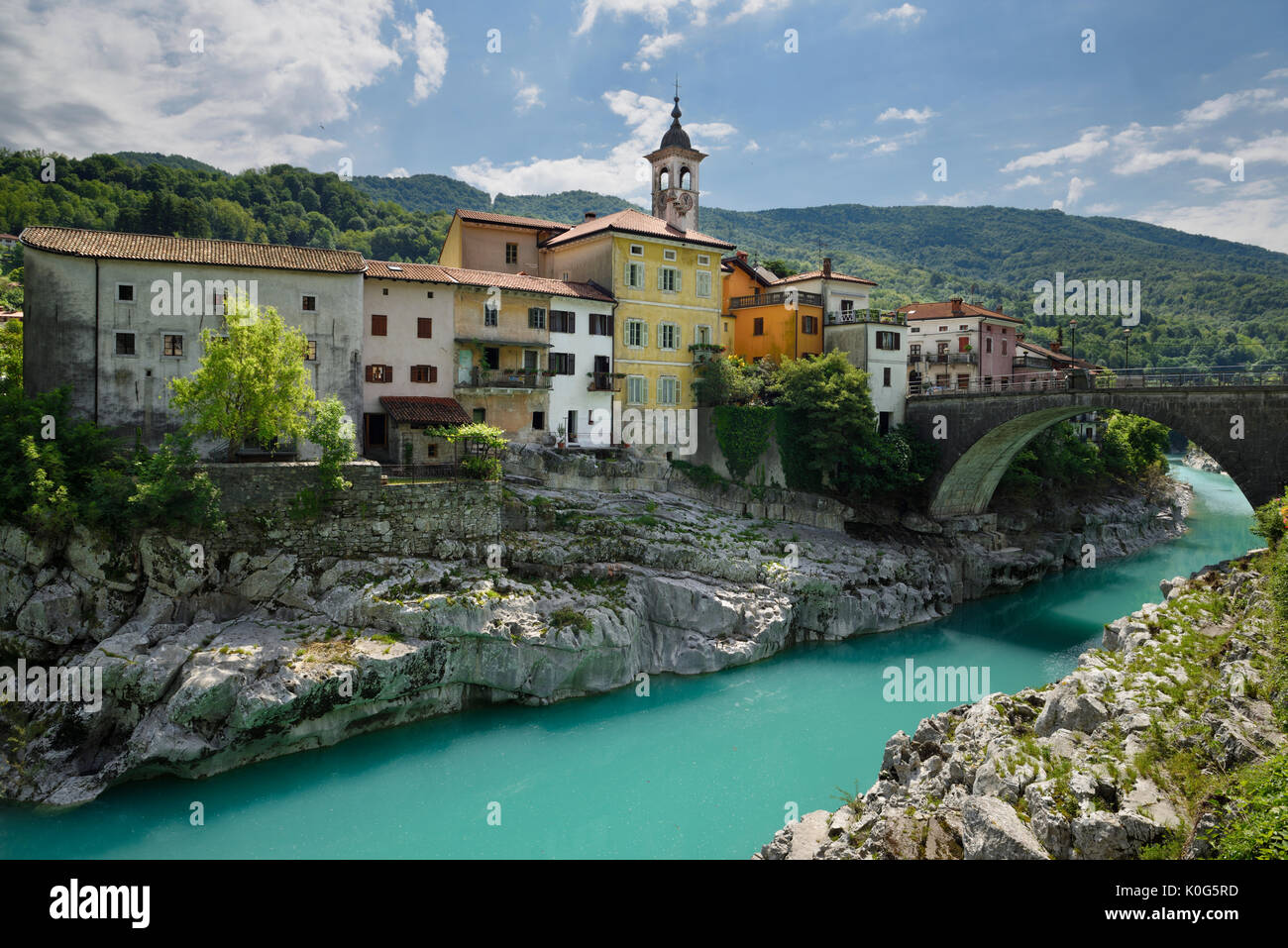 Stucco di colorate case sul turchese Soca River con ponte in pietra a sezione antica di Kanal Slovenia con assunzione di Maria la Chiesa Foto Stock